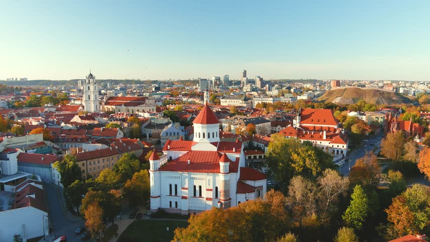 Beautiful aerial Vilnius city Old town panorama in autumn with orange and yellow foliage. Aerial sunny evening view. Cathedral of the Theotokos. Fall city scenery in Vilnius, Lithuania