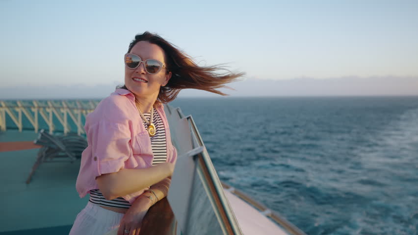 A woman finds joy as she admires the tranquil and stunning view from a cruise ship, watching the sun gracefully disappear over the ocean, embodying the perfect blend of relaxation and adventure
