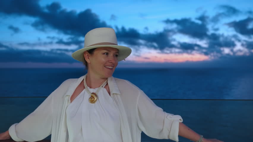 An absolutely stunning view of a woman fully enjoying a vibrant sunset while aboard a cruise ship, all beautifully captured against a captivating backdrop of serene ocean waves and colorful skies