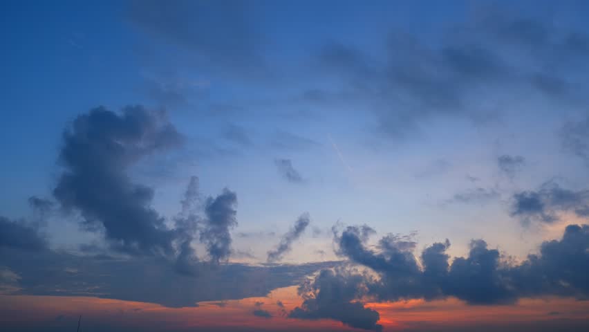 Golden sunrise time-lapse blooms softly across the sky, blending pastel oranges and pinks with calm blue. Clouds drift gently, glowing warmly as dawn’s light awakens a new day’s promise. Timelapse.
