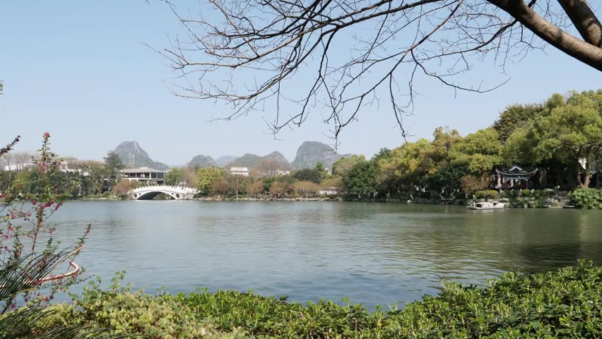 A tranquil lake reflects the trees and buildings in a scenic park