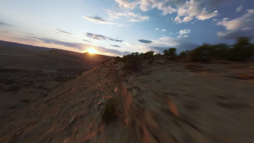 FPV Drone Flying Along Desert Ridge into Sunset Near Red Rocks