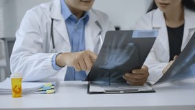 Medical team collaborating around hand x ray, carefully reviewing bone structure and discussing potential diagnosis with professional expertise - Powered by Shutterstock - Get 15% off with code: PIKWIZARD15