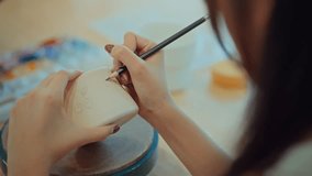 Close-up of female artist’s hands sketching design with pencil on handmade ceramic pottery before painting – creative hobby, traditional craft and artistic expression in calm studio workshop setting - Powered by Shutterstock - Get 15% off with code: PIKWIZARD15