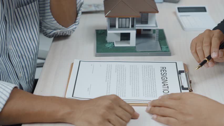Real estate agent pointing a pen to the contract conditions and showing to the client where to sign