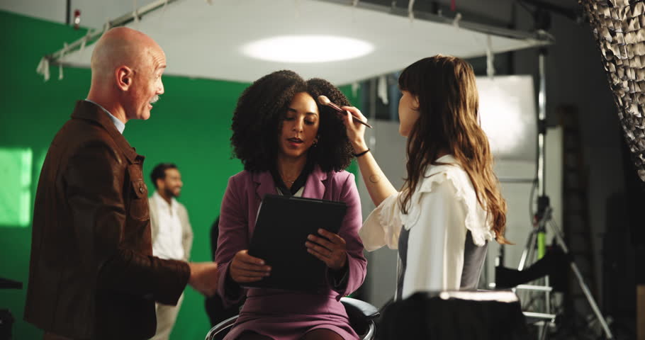 Clipboard, high five and makeup with director on set for advertising or production success. Behind the scenes, green screen and styling with people speaking in studio for videography satisfaction
