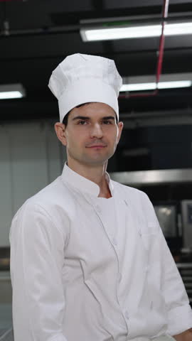 Portrait of confident male chef wearing uniform standing with arms crossed in professional restaurant kitchen, looking confident.