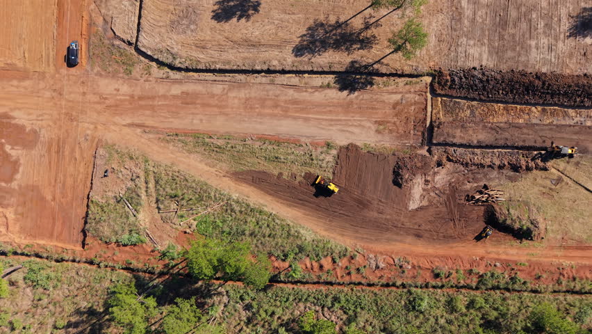 High-altitude view captures synchronized machinery reshaping terrain under sunlight. Ideal for construction reels or equipment demos.
