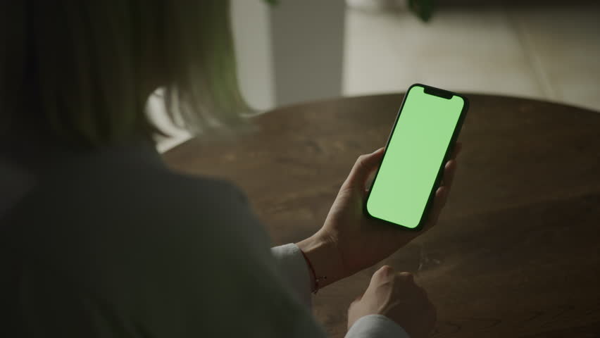 Woman Tapping Green Screen Smartphone Indoors