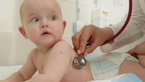 A baby is examined by a doctor with a stethoscope, focusing on their health and well-being. The child lies on a table during the medical checkup. Doctor Examining Baby - Powered by Shutterstock - Get 15% off with code: PIKWIZARD15