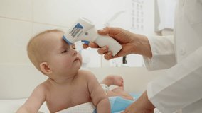 A doctor checks a baby's temperature using a non-contact thermometer during a medical checkup. Doctor Checking Baby's Temperature. Doctor Examining Baby - Powered by Shutterstock - Get 15% off with code: PIKWIZARD15