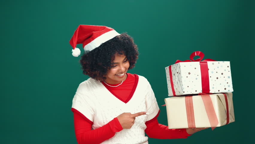 Studio, pointing and woman with gift, excited and celebration for Christmas, smile and mockup space. Happy, face and black person with present for festive season, green background and giveaway or box