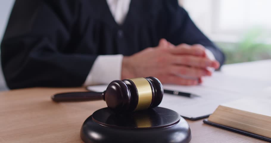 Close-up of judge using gavel or mallet in courtroom during government session, delivering verdict and judgment on law enforcement, focusing on sentence in a professional setting with authority.