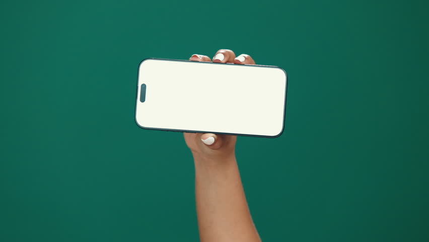 Person, hands and phone screen with mockup in studio for advertising on a green background. User, model or display with mobile smartphone for new app, social media platform or UI marketing on space