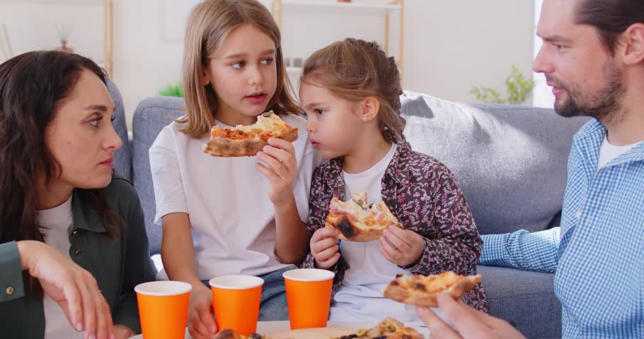 Happy family at home, parents and children taking sharing tasty pizza slices from box on table, eating together enjoy lunch at break, using fast food delivery service, enjoy weekend time together