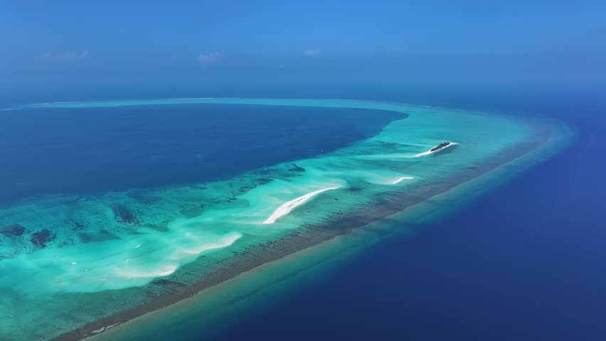Aerial view of the stunning turquoise and dark blue waters surrounding a long, winding sandbank at Fulhadhoo Island, Baa Atoll, Maldives.