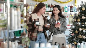 Women buy nail polishes and a set of makeup cosmetics against the background of a Christmas tree in the supermarket. Customers choose a set of cosmetics for festive New Year promotions and discounts - Powered by Shutterstock - Get 15% off with code: PIKWIZARD15