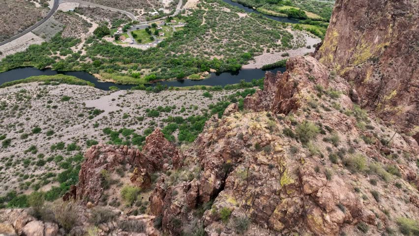 Aerial view of the Roosevelt Dam and the winding river, contrasting the arid landscape with the vibrant water, Tonto Basin, Arizona, United States.