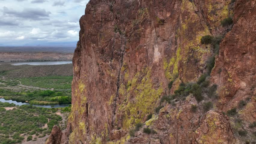 Aerial view of a rugged cliff face with a lake in the background, showcasing the stark contrast between the rock and water, Mesa, Arizona, United States.