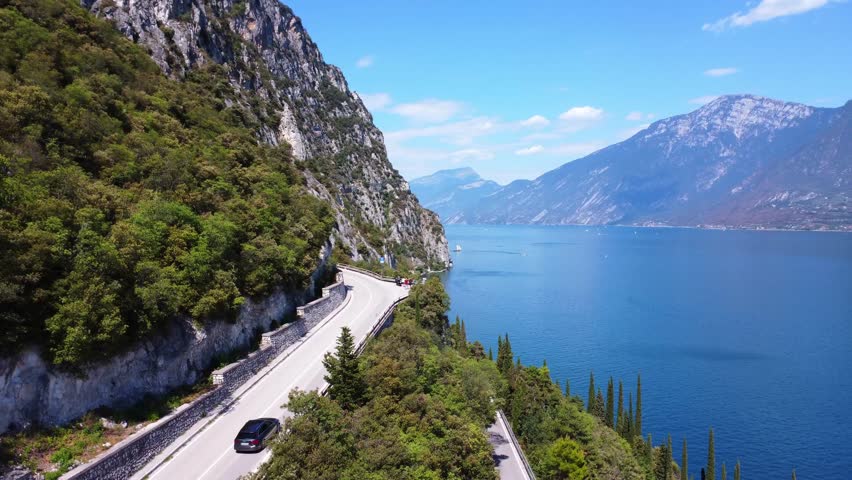 Drone shot of Strada della Forra curving through cliffs above Lake Garda. This legendary Italian road offers tunnels, dramatic drops, and one of Europe’s most scenic drives.