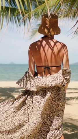 Travel in summer vacation, back view of beautiful woman moving to sea beach, enjoy freedom. Carefree lady walking alone on coastline, sun protection and UV protection for skin, gorgeous female person