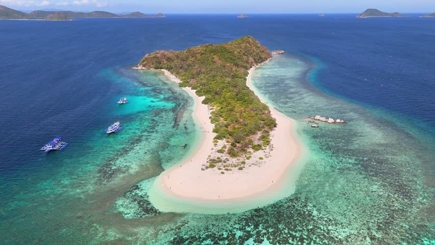Aerial view of Manlihan Island in Linapacan, Philippines featuring turquoise waters, coral reefs, boats, and lush greenery surrounded by the vast Sulu Sea