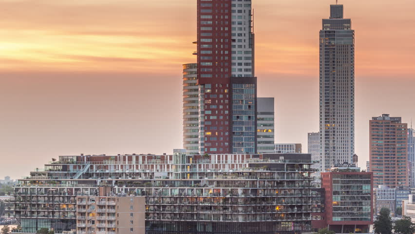 Aerial day to night transition timelapse of Katendrecht peninsula and Maashaven harbour in Rotterdam, The Netherlands. City skyline modern skyscrapers and traditional Dutch waterfront houses