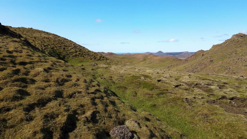 Aerial view of the tranquil Trolladyngja crater lake nestled amongst rugged, undulating hills under a clear blue sky, Grindavik, Grindavíkurbaer, Iceland.