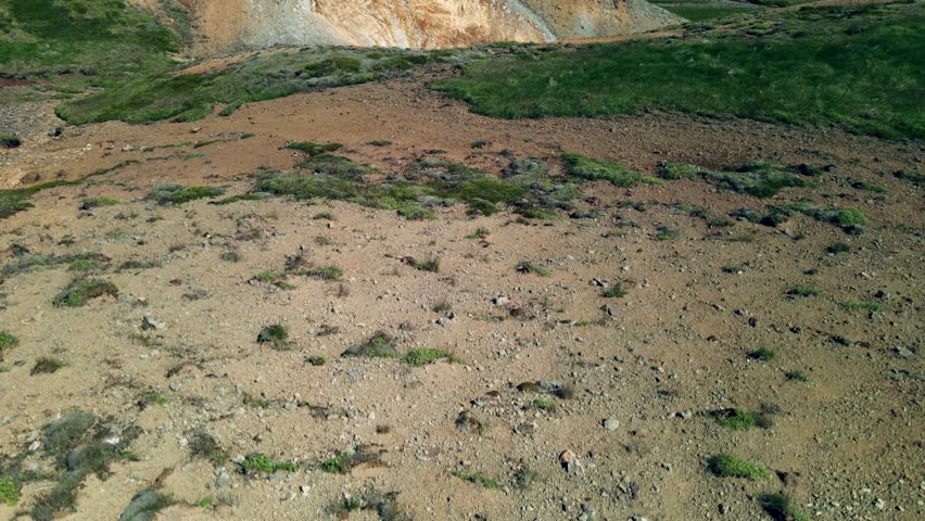 Aerial view of the stark contrast of lush green hills meeting the arid, textured earth in the Grensdalur landscape, Hveragerði, Sveitarfélagið Olfus, Iceland.