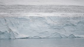 Expansive frozen glacier wall stretching across a calm icy landscape, showcasing the immense scale and solid blue-and-white layers of ancient ice formations. - Powered by Shutterstock - Get 15% off with code: PIKWIZARD15