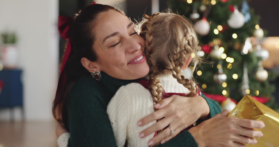 Christmas, hug or present with mother with daughter in living room of home for festive celebration. December, gift or thank you with girl child and single parent embracing in apartment for holidays
