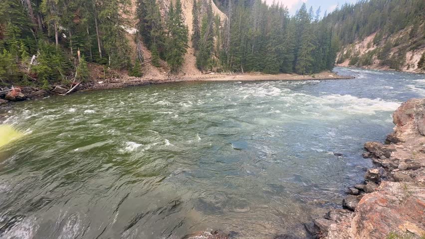 Fast-flowing Yellowstone River dropping over the edge of the Lower Falls in Yellowstone National Park. Panning right to left.