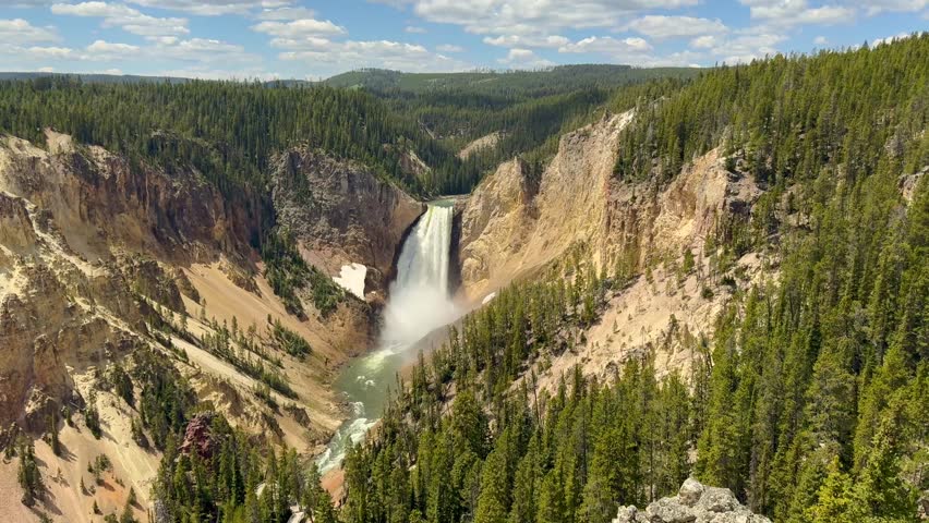 Scenic landscape view of the fast-flowing Yellowstone River dropping over the edge of the Lower Falls in Yellowstone National Park. 
