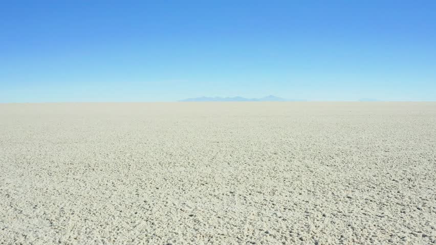 Aerial view of the vast, cracked white expanse of Salar de Uyuni merges seamlessly with the clear blue sky, Potosi Department, Bolivia.