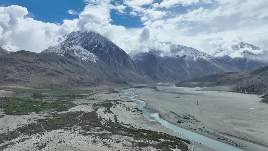 Aerial view of the majestic mountains with snow-capped peaks and a winding river cutting through the rugged terrain, Ladakh, Ladakh Division, India.