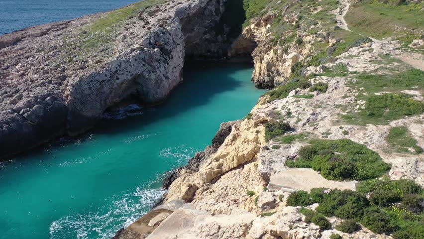 Aerial view of the rugged Gozo coastline meets the clear turquoise waters, with a cave opening to the sea, creating a stunning contrast, Gozo island, Malta.