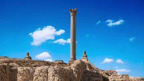 Pompey's Pillar, Roman triumphal column, with two Sphinx statues located at the Serapeum of Alexandria. Ancient architectural landmark in Egypt.The view of Pompey's Pillar against the background of a  - Powered by Shutterstock - Get 15% off with code: PIKWIZARD15