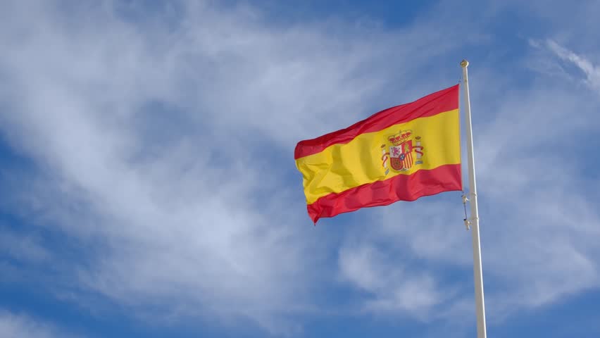 Spanish flag waving gracefully against a bright blue sky. A powerful symbol of national pride, unity, and heritage, capturing the essence of Spains cultural identity