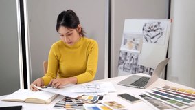 An adult Asian woman designs a UI project using color swatches, laptop, and design drawings. She focuses on creating innovative user interface for application. - Powered by Shutterstock - Get 15% off with code: PIKWIZARD15