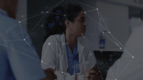 Female doctor tapping tablet while displaying network graphic overlay guiding medical team meeting. Medical, collaboration, modern, professional, healthcare, technology, communication - Powered by Shutterstock - Get 15% off with code: PIKWIZARD15