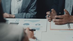 Business professionals collaborating on financial charts, intently analyzing data and taking detailed notes during strategic meeting at modern office workspace - Powered by Shutterstock - Get 15% off with code: PIKWIZARD15