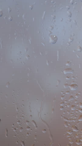 Raindrops gently slide down a window during a gloomy evening, creating a calm and moody ambiance. Perfect for conveying solitude, reflection, peaceful moments, or emotional storytelling.