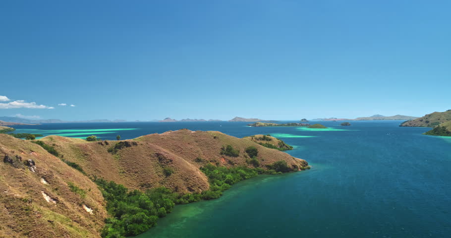 Aerial view of Padar island in Komodo national park, Indonesia, showcasing the stunning turquoise bays, lush green hills, and the vast expanse of the ocean under a vibrant blue sky