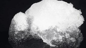 Melting ice cubes dissolve slowly over a glossy black reflective surface in a timelapse footage. Strong studio lighting enhances reflections and surface texture. - Powered by Shutterstock - Get 15% off with code: PIKWIZARD15