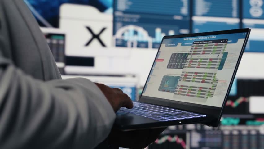 Black business manager using his laptop to examine fintech insight, reading big data and KPI metrics in order to build a new vision. Leadership and management skills. Close up. Camera B.