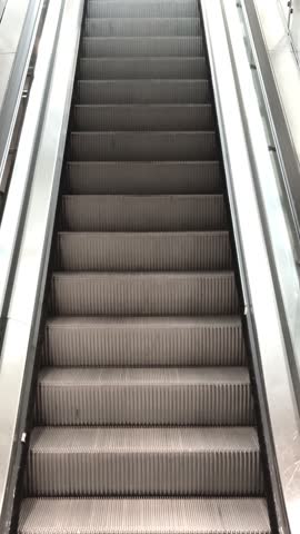 Upward view of empty escalator in bright indoor space, symbol of progress, motion or transportation concept, vertical video