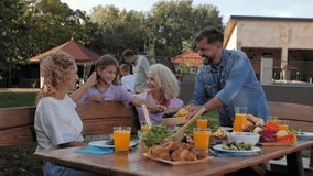 Multigenerational family gathering around outdoor dining table, sharing heartwarming meal with joyful interaction and genuine connection during sunny day - Powered by Shutterstock - Get 15% off with code: PIKWIZARD15