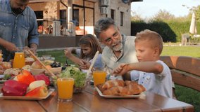 Multigenerational family enjoying sunny outdoor lunch, sharing delicious meal and laughter in garden setting with grandparents, parents, and children - Powered by Shutterstock - Get 15% off with code: PIKWIZARD15