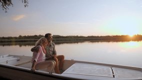 Mature couple sharing tender moment while sitting closely, embracing during golden hour sunset over tranquil lake waters, reflecting peaceful retirement lifestyle - Powered by Shutterstock - Get 15% off with code: PIKWIZARD15