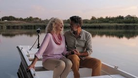 Senior couple sharing tender moment while holding hands, enjoying romantic boat ride during golden sunset light on tranquil water surface - Powered by Shutterstock - Get 15% off with code: PIKWIZARD15